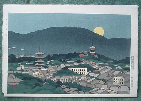 a town as the moon is rising over the mountains